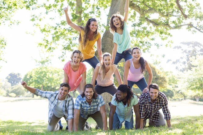 Happy friends in the park making human pyramid on a sunny day.jpeg